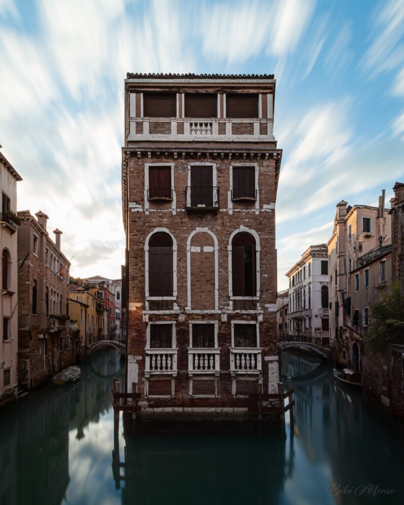Palazzo Tetta in Venice framed by two canals, photographed in the early morning with a 60-second exposure that stretches the clouds across the sky above the building and softens the water below.